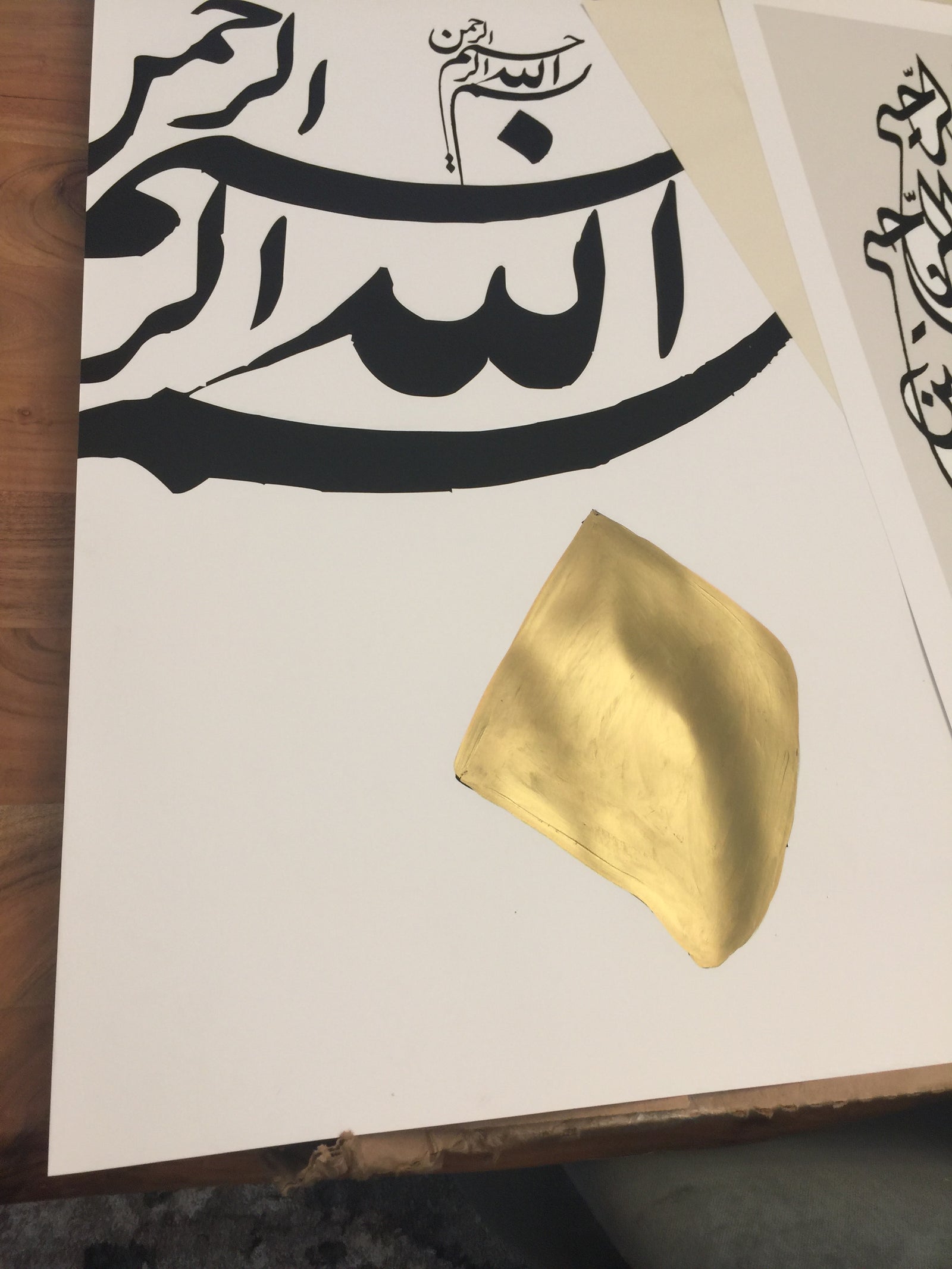 Gold leaf on a piece of paper with black and white calligraphy arabic designs